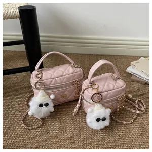 Primer plano detallado del bolso vanity rosa acolchado con elegante correa de cadena y peluche.