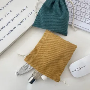 Detail of corduroy drawstring makeup pouches with cosmetics inside on an office desk