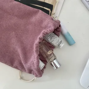 Detail of purple corduroy drawstring makeup bag showing soft ribbed fabric texture