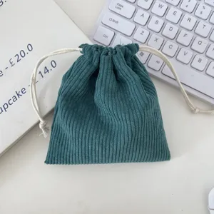 Close-up of a dark green corduroy drawstring cosmetic pouch on desk