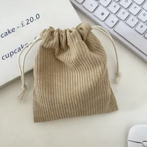 Detailed view of a beige corduroy drawstring pouch showing texture on a white desk