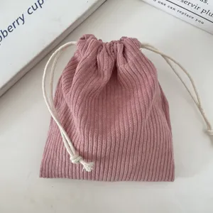 Close-up of pink corduroy drawstring pouch showing soft ribbed texture and white cotton cords.