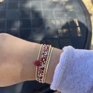 Multi-layer beaded bracelet for women featuring a stylish red clover charm and gold beads.