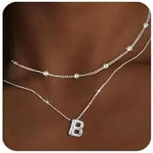 Primo piano dettagliato della collana a strati con lettera e catenine delicate e perline.
