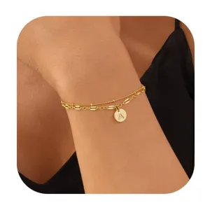 Gros plan sur les détails d'un bracelet doré double couche avec un pendentif rond lettre A.