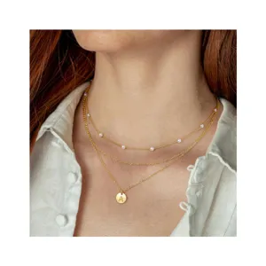 Gelaagde goudkleurige ketting met delicate parels en een stijlvolle letter munt hanger voor dames.