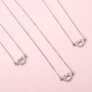 Detail view of the silver-tone love knot necklace set featuring delicate chains and cute charms.