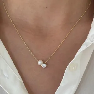 Delicate gold-tone chain necklace featuring a smooth pearl and sparkling solitaire pendant.