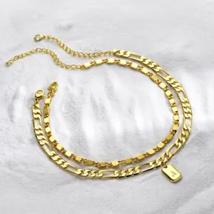 Double layer gold-colored stainless steel cuban chain anklet with letter A tag pendant.