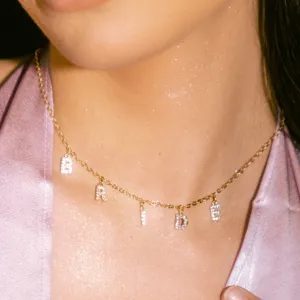 Close up detail shot of sparkly rhinestone letter BRIDE pendant necklace on gold chain.