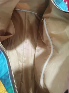 Travel bag interior detail shot showing smooth golden brown lining, zipper pocket and slip pocket.