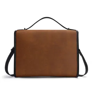 Detalle de bolso de cuero PU marrón, ribete negro y asa, elegante bolso cruzado de hombro.