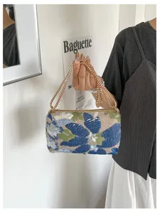 Detailopname van een chique geborduurde handtas met pailletten en een gouden ketting.