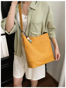 Detailed close-up view of a stylish yellow woven leather bucket bag with an adjustable strap.