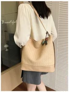 Detail shot of a chic beige woven bucket bag with smooth leather trim and charming bead accessory.