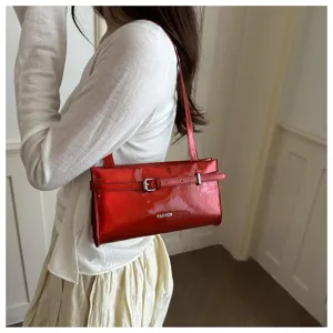 Detail shot of the stylish red patent leather underarm bag showcasing its chic buckle design.