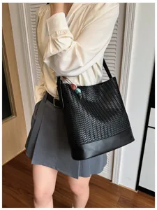 Detailed view of the black woven bucket bag worn by the model, showcasing texture and style.