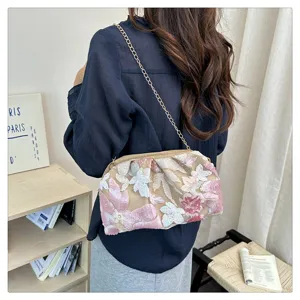 Dettaglio in primo piano della borsa a tracolla chic con paillettes e catena dorata.
