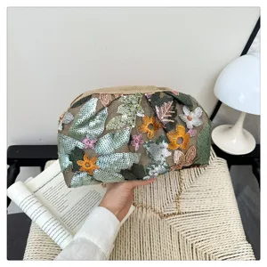 Dettaglio ravvicinato della borsa da sera con catena e ricamo floreale di paillettes.