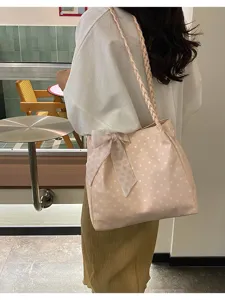Vista detallada del bolso tote de lunares rosa con correa trenzada y bonito lazo elegante.