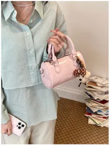 Detail shot of a cute pink patent leather barrel bag with a fluffy puppy plush charm accessory.