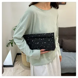 Λεπτομερής κοντινή λήψη της μαύρης τσάντας clutch με μοτέφ αστέρων, μαλακό ύφασμα και κομψή εμφάνιση.