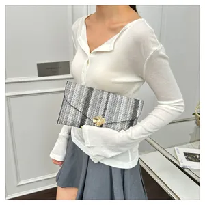 Detailed view of the chic black and white striped woven clutch with metallic clasp.