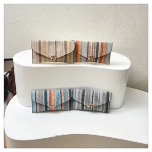 Colorful woven clutch bag with gold-tone hardware, trendy striped design for women.