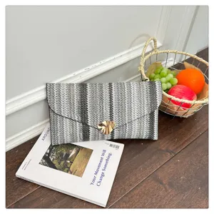 Detailed view of a chic woven envelope clutch bag with striped pattern and gold clasp.
