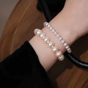 Detailopname met gestapelde parelarmbanden gedragen om de pols op een mooie houten achtergrond.