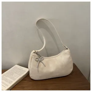 Detailed view of trendy frosted underarm shoulder bag with delicate beaded bow pendant charm.