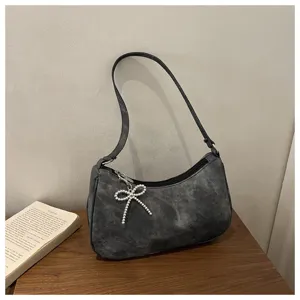Detailed view of the dark frosted shoulder bag featuring a chic pearl bow zipper charm.