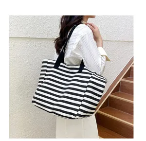 Close-up detail of casual striped canvas tote bag showing spacious capacity and shoulder strap.