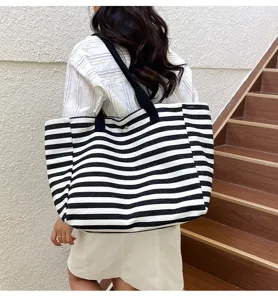 Detailed view of the black and white striped canvas tote bag worn on shoulder, showing large capacity.
