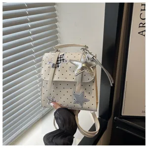 Detailed view of the preppy style polka dot mini backpack with cute star patches and charm.