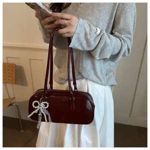 Burgundy pillow handbag detail featuring elegant dual shoulder straps and a cute pearl bow pendant.