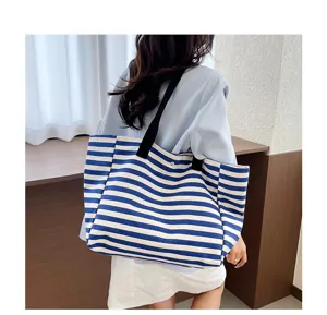 Detailed view of the blue and white striped canvas tote bag worn on shoulder, showing capacity.