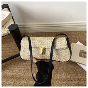Vue de détail d'un sac baguette en paille tressée avec bordure en cuir noir et fermoir métallique.