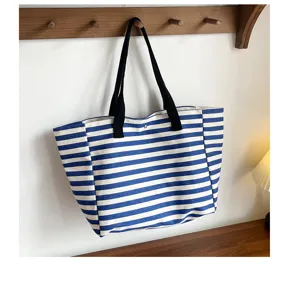 Blue and white striped canvas tote bag hanging detail, showing durable black straps and fabric.