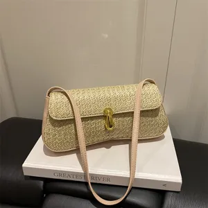 Sac à épaule baguette en paille tissée pour femme avec serrure dorée et lanière rose.