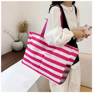 Detail view of the pink and white striped beach tote bag worn by model, casual style.