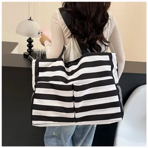 Detail shot of a black and white striped canvas tote bag with large capacity and shoulder strap.