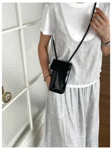 Black patent leather phone crossbody bag detail, chic vertical small square bag for women.