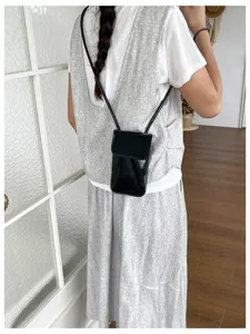 Glossy black vertical phone crossbody bag, stylish women mini sling pouch for daily outfit detail.