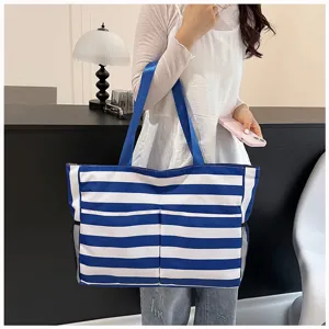 Detail shot of a blue and white striped canvas tote bag with shoulder straps and mesh side pockets.