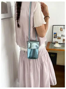 Metallic shiny vertical phone crossbody bag detail, compact chic single shoulder strap style.