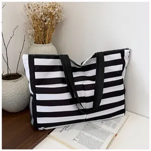 Black and white striped canvas tote bag scene detail showing spacious design and dual straps.