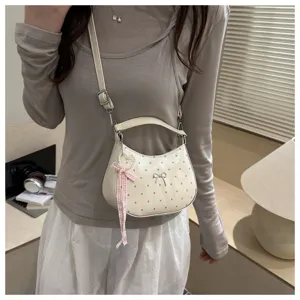 Casual polka dot crossbody bag for women, stylish dumpling handbag with bow and ribbon charm.