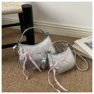 Silver metallic polka dot dumpling handbag with pink bow and pearl charm, detail view.
