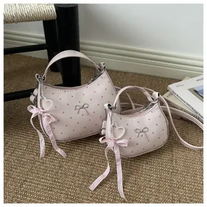 Close-up detail of the pink polka dot dumpling bag featuring cute bow and pearl charm decor.